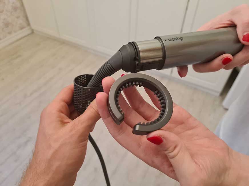 Man sieht, wie der Dyson Airwrap mit der Filterreinigungsbürste gesäubert wird. 